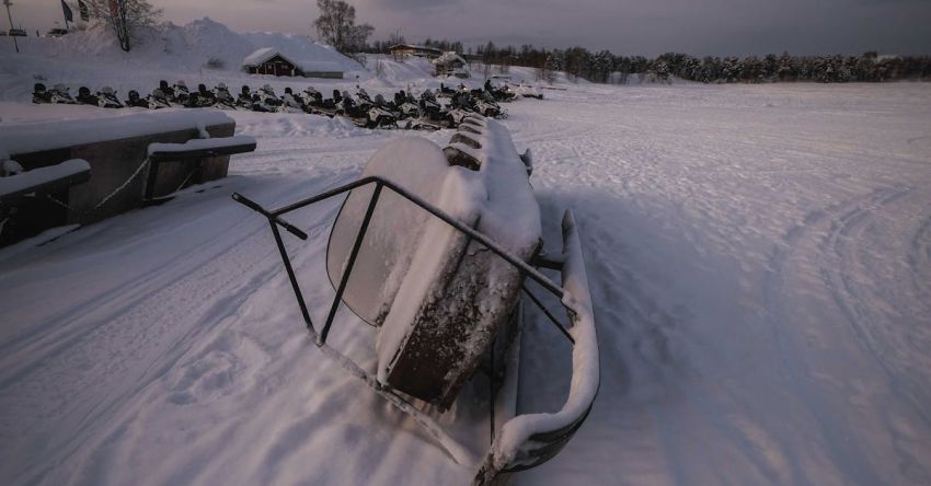 Snowmobile Trails - Forgotten snowmobile covered with hoarfrost and placed on side on snow in winter time in field against cloudy sky