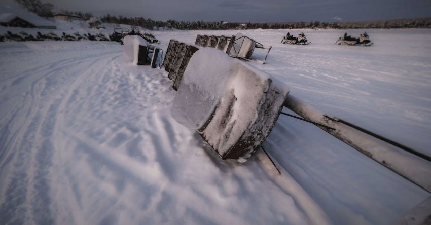 Snowmobile Trip - Snowmobile covered in ice placed on side on snow in field with forest in distance in winter time in nature outside