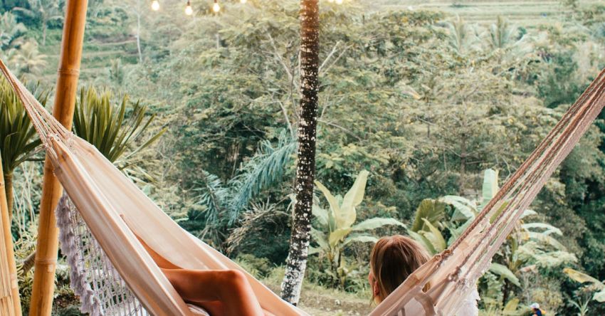 Cottage Vacation - Slender woman resting in hammock under glowing garlands