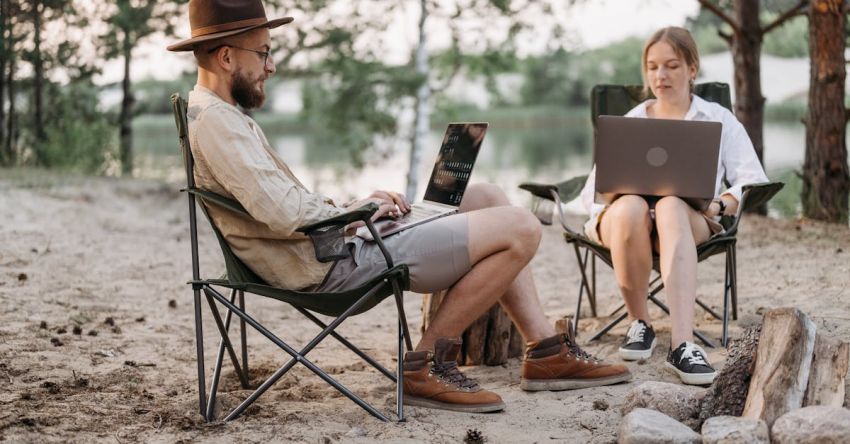 Camping Gadgets - A Couple Having Conversation while Working at the Campsite