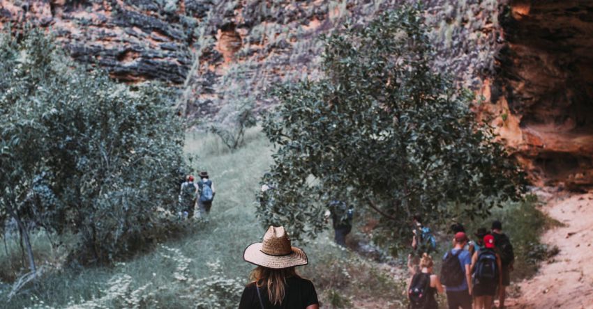 Wildlife Tours - Travelers walking on sandy ground through steep stony mountains while exploring nature during trip